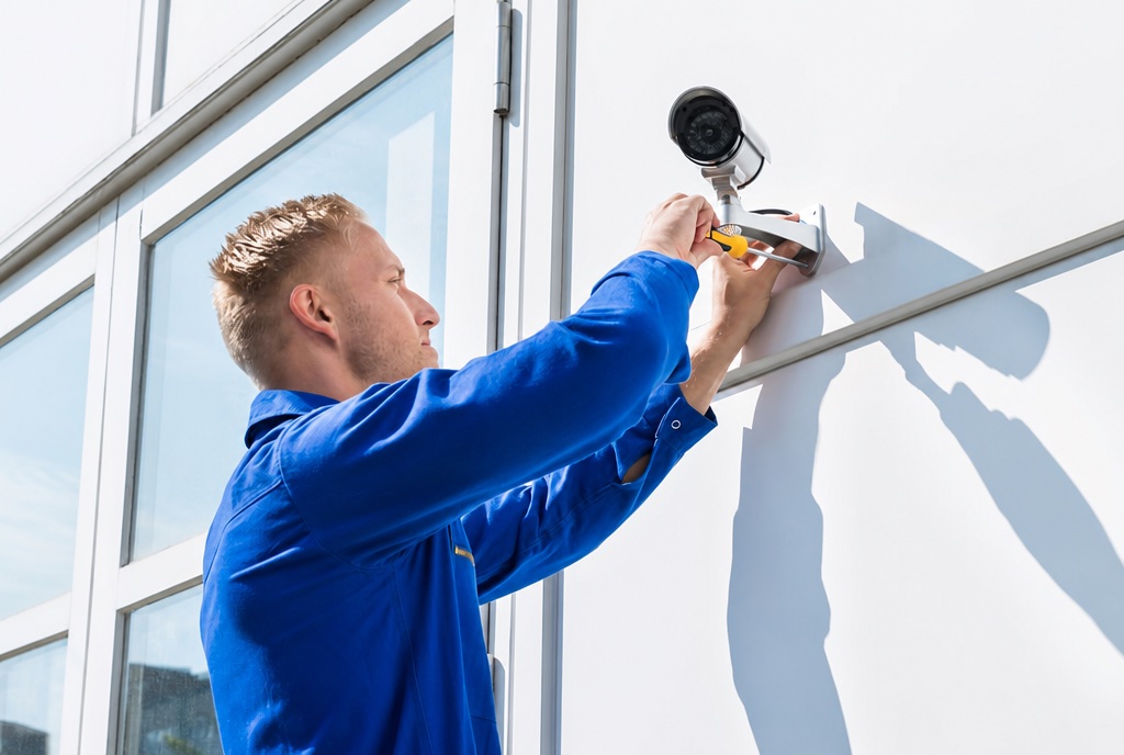 Technician installing a commercial security camera on a New York business building